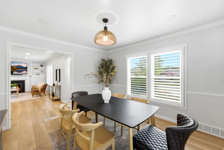 Modern dining area featuring a black wood-top table, natural wood chairs with woven seating, and a curved black leather accent chair
