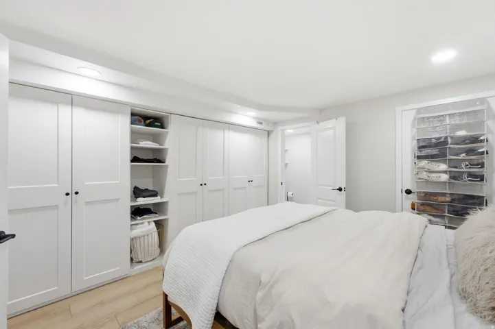 Primary Bedroom Suite with Custom Built-In Cabinetry and Abundant StorageThis spacious primary bedroom features extensive custom white cabinetry with multiple closets and open shelving, providing generous storage throughout