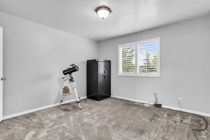 Gray carpeting, neutral wall finishes, and a window with white louvered shutters