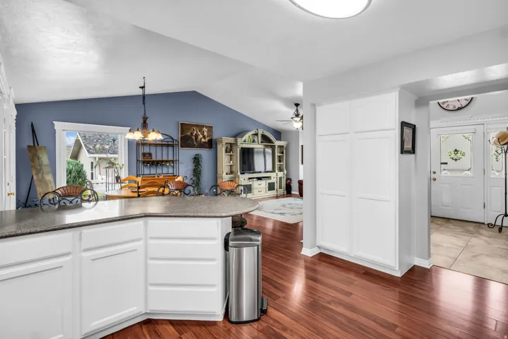 Kitchen island with white cabinetry and dark-toned countertop, wood-finish flooring, and built-in storage cabinetry