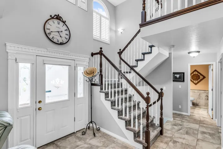 Two-story entryway with a decorative front door, transom windows, and an arched window with plantation shutters