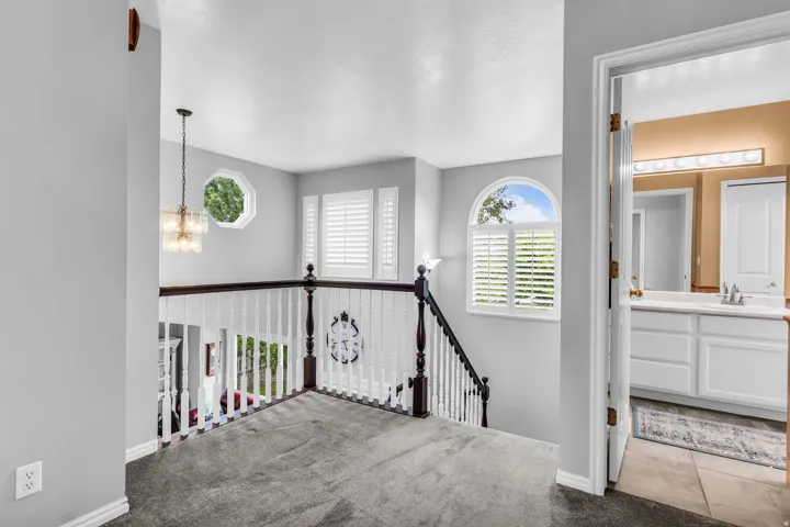 Staircase featuring dark wood newel posts, white balusters, and gray carpeting