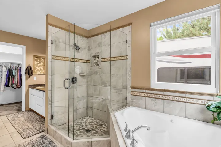 Tile-surround soaking tub and a separate glass-enclosed shower with mosaic tile floor