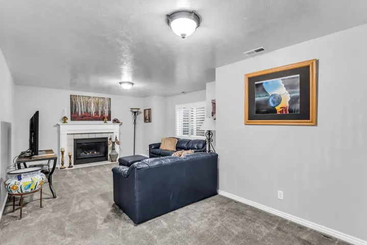 Living space featuring a fireplace with a decorative mantel, neutral wall paint, and gray carpeting