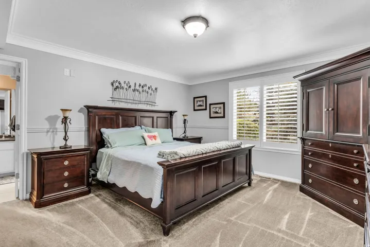 Recessed ceiling with crown molding, two-tone wall paint, window with plantation shutters, and a ceiling-mounted light fixture