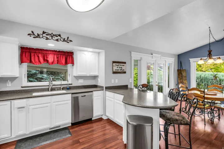 Kitchen featuring white cabinetry, stainless steel appliances, a breakfast bar, wood-finish flooring, and a dining area with direct outdoor access