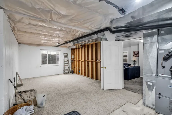 Unfinished basement area featuring a window, exposed framing, and existing mechanical systems