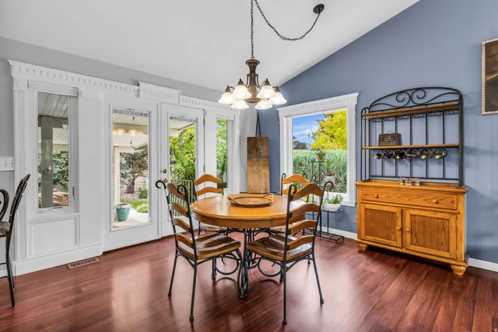 Vaulted ceiling with a chandelier, wood-finish flooring, white trim details, and glass paneled doors