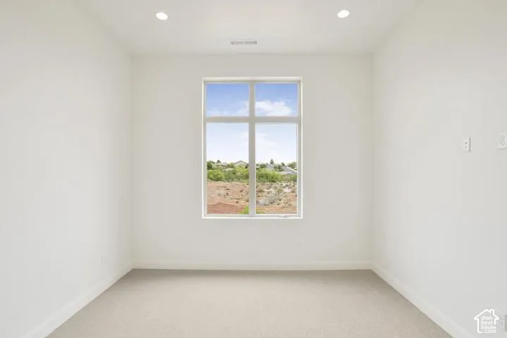 Recessed ceiling lighting, neutral carpeting, window with multiple panes, white walls, and white trim