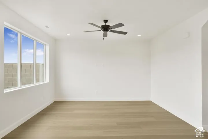 Recessed lighting, ceiling fan, expansive window, light wood-finish flooring, and white walls