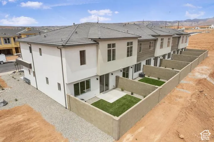 Townhome exterior featuring a stucco finish, tiled roof, and private walled courtyards with synthetic turf
