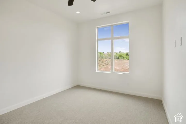 Recessed lighting, ceiling fan, white walls, carpeted flooring, and large window with exterior scenery