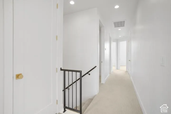 Hallway with recessed lighting, light-toned carpeting, and white walls