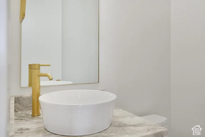 Vessel sink with a brushed brass faucet, set on a stone countertop
