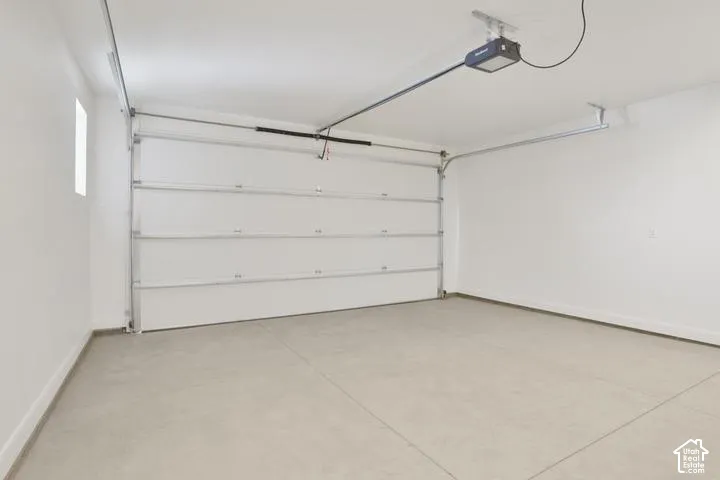 Attached garage with a white sectional door, painted interior walls, and an automatic opener