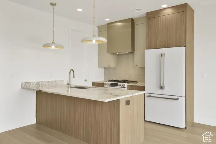Kitchen with a central island featuring a stainless steel sink, light-toned wood-finish cabinetry, and light-colored countertops