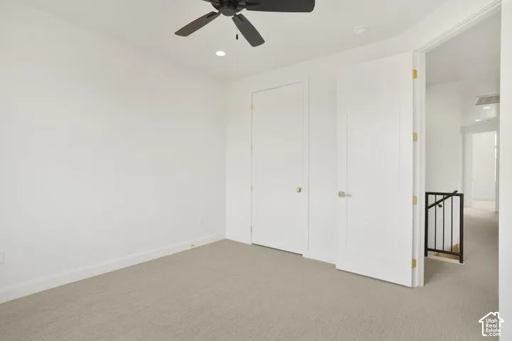 Recessed ceiling lighting, ceiling fan, neutral wall paint, light-toned carpeting, and white doors