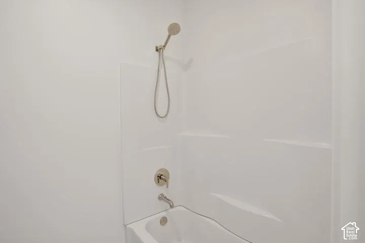 Bathtub with a shower combination, smooth white surround, and brushed nickel fixtures