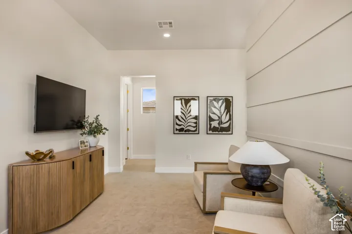Recessed lighting, light-toned walls, and neutral carpeting