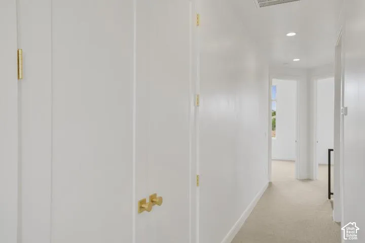 Neutral wall paint and carpeting throughout, featuring recessed lighting and brass-finish hardware