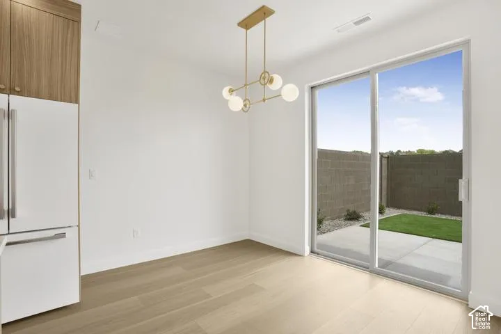 Clean white walls, wood-finish flooring, and a contemporary linear chandelier