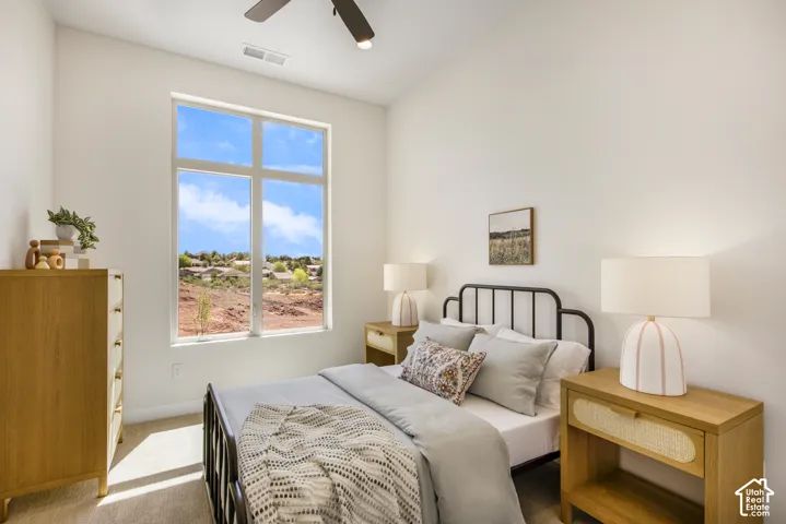 Vaulted ceiling with an attached ceiling fan, large multi-pane window, and neutral-toned carpeting