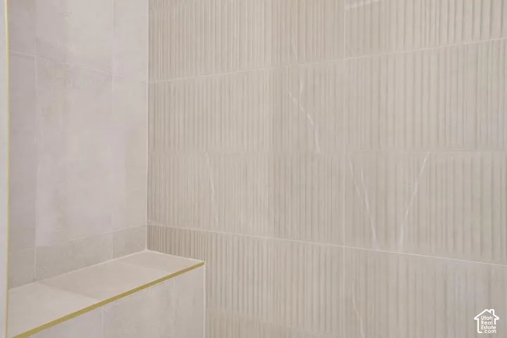Recessed shower bench with a gold-finish trim, complemented by vertical textured wall tiling and large format wall tiles