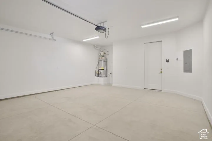Spacious garage featuring a concrete floor, bright overhead lighting, and an automatic garage door opener