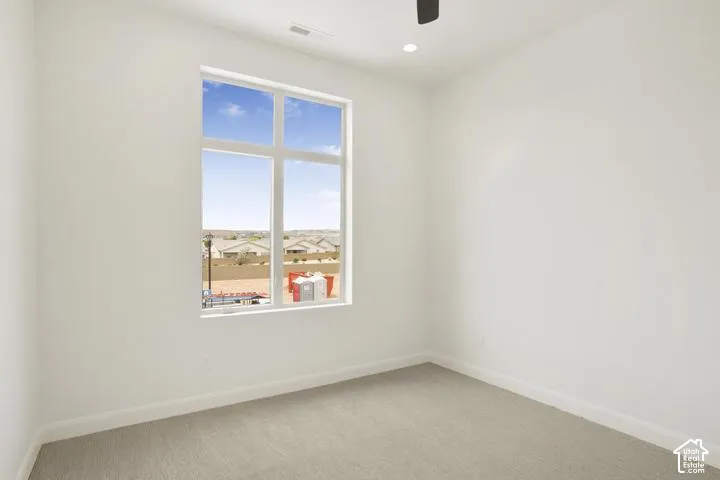 Large window with multiple panes, recessed ceiling lighting, ceiling fan, and light gray carpeting