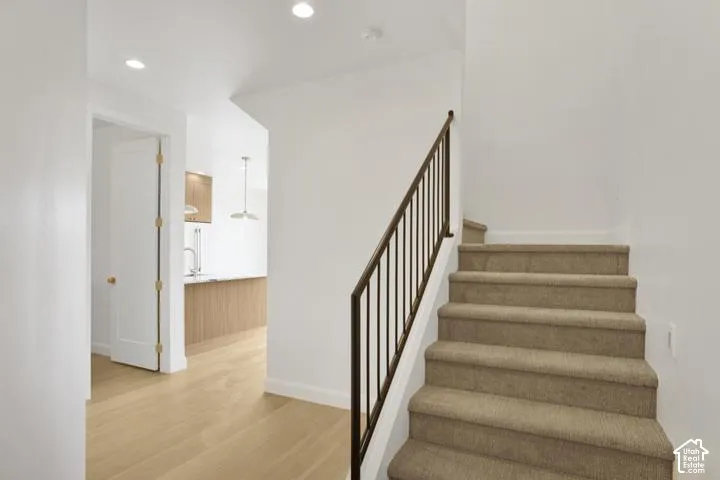 Recessed ceiling lighting, wood-finish flooring, metal staircase railing, and carpeted stairs