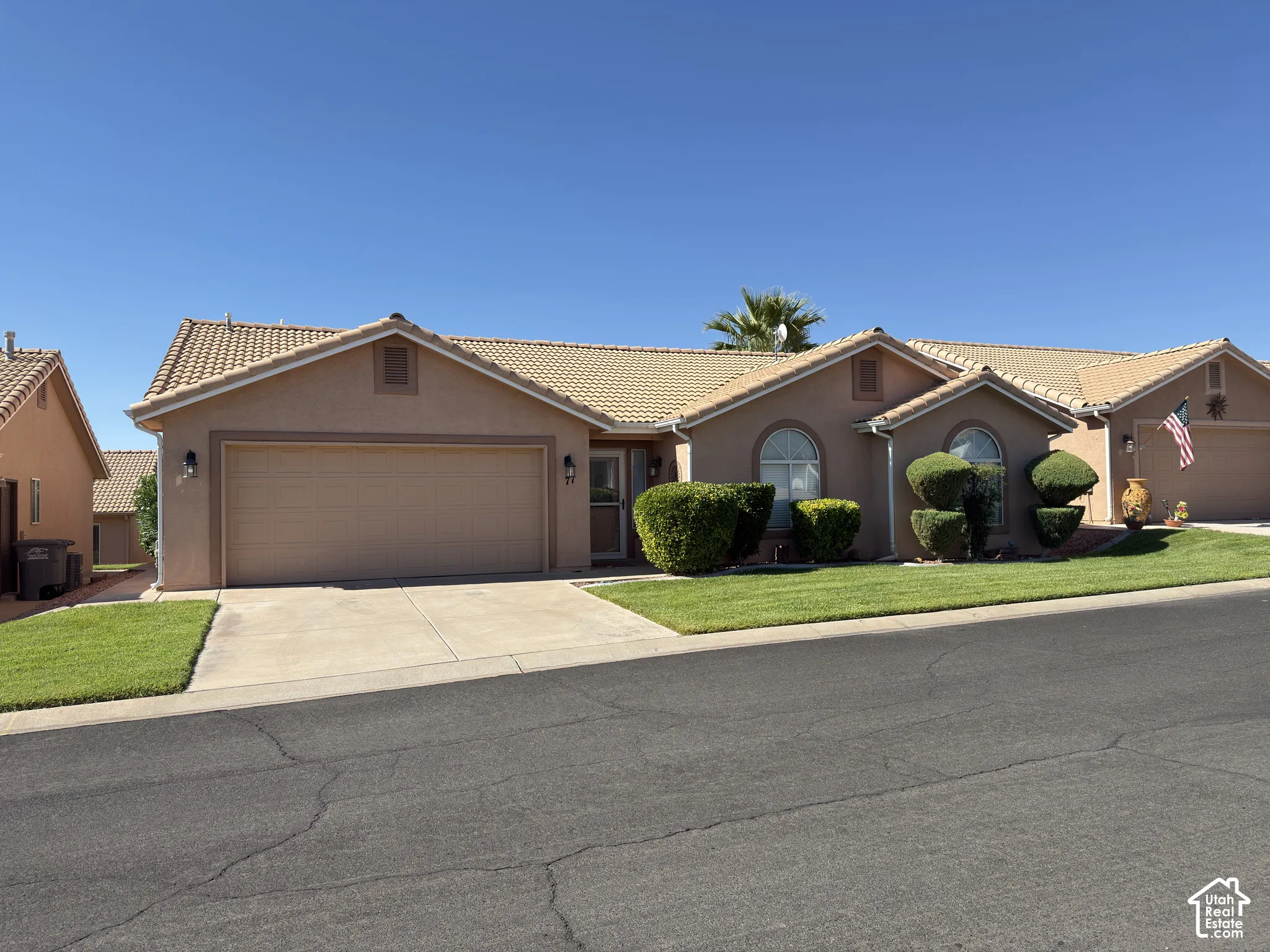 Stucco exterior with a tiled roof, front-facing garage, arched windows, and a landscaped front yard