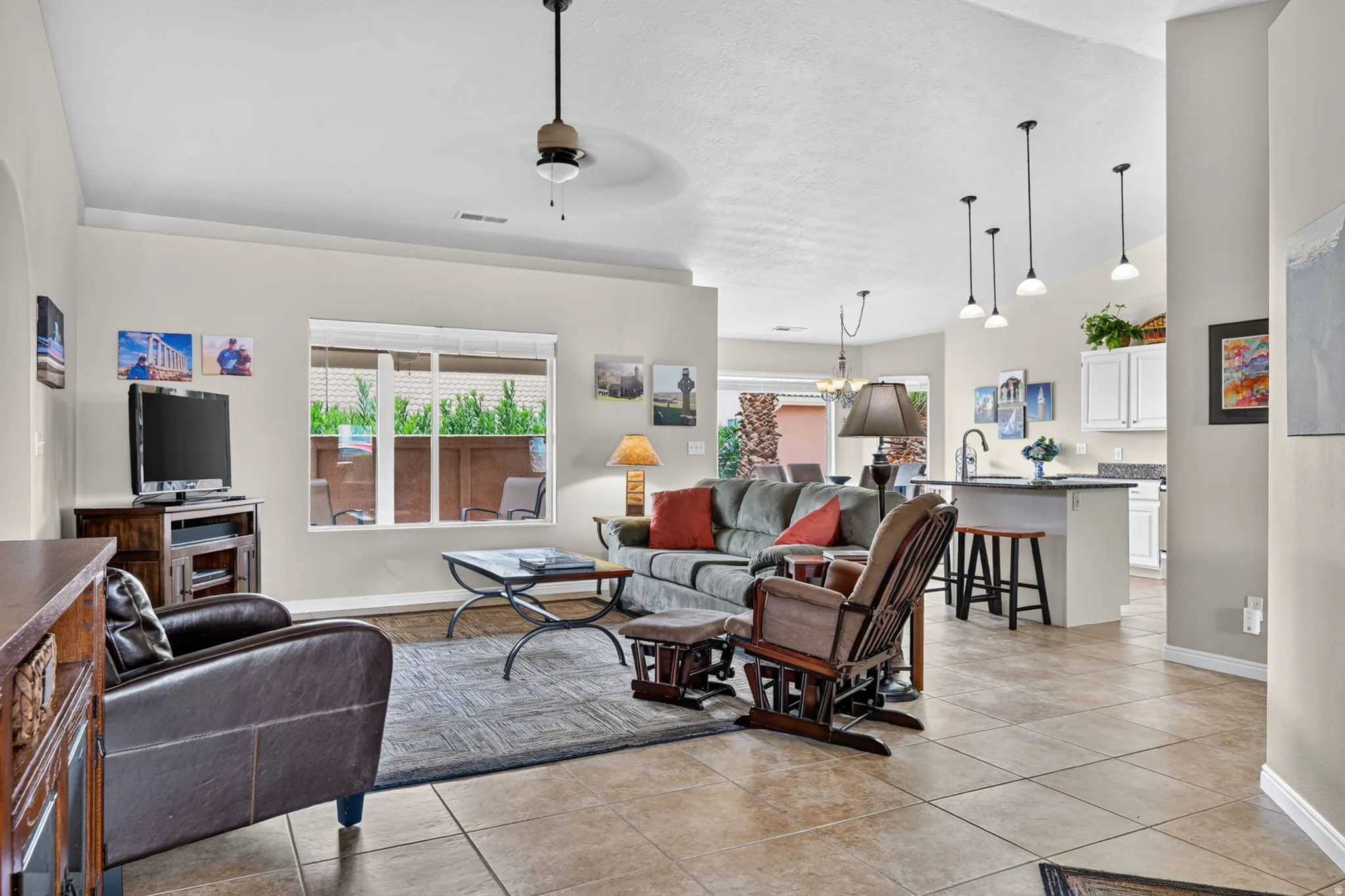 Open-concept living area featuring tile flooring, a ceiling fan, and pendant lighting
