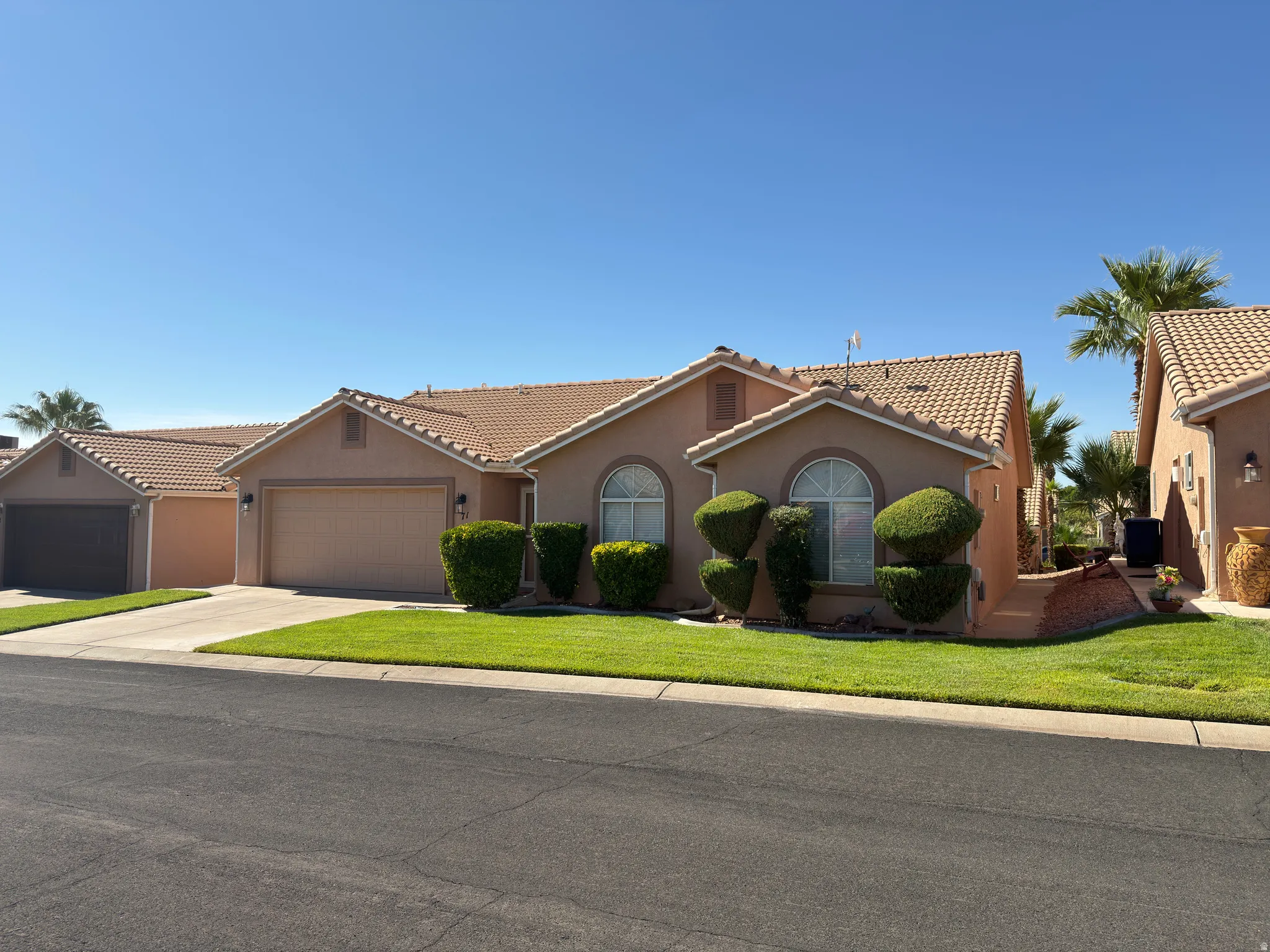 Stucco exterior with a tile roof, arched windows, and an attached garage