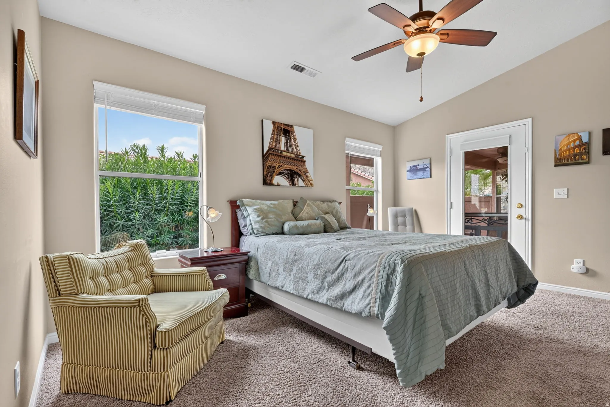 Vaulted ceiling with a ceiling fan, carpet flooring, multiple windows, and a glass-paneled exterior door