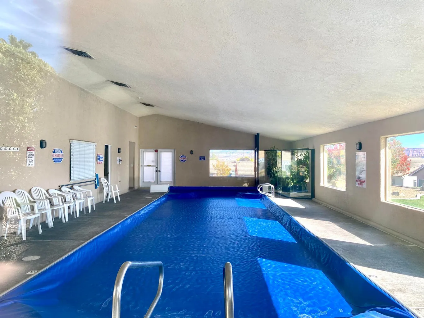 Indoor swimming pool featuring a blue pool cover, sloped ceilings, and multiple windows