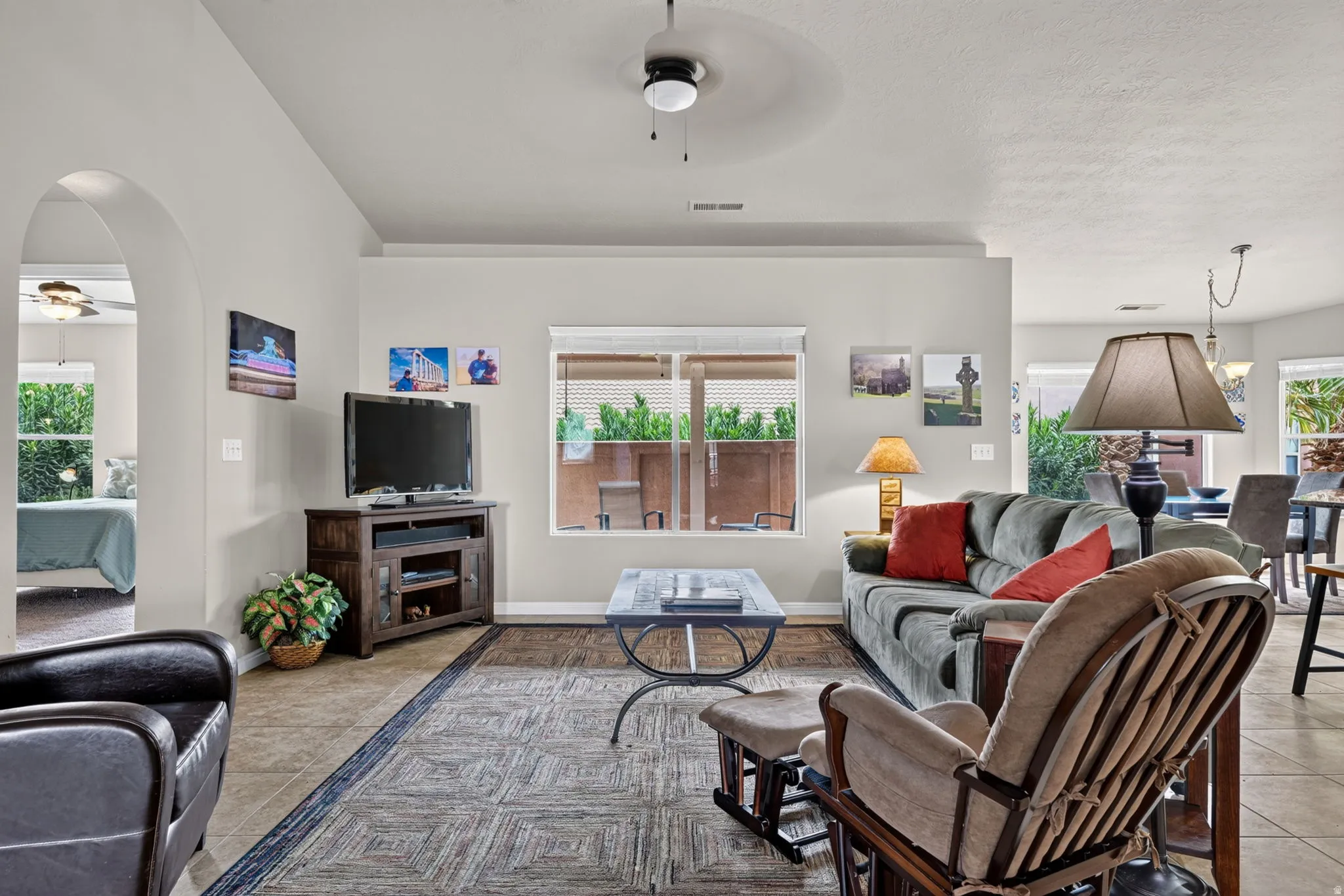 Living area featuring tile flooring, a window with outdoor scenery, and an arched doorway