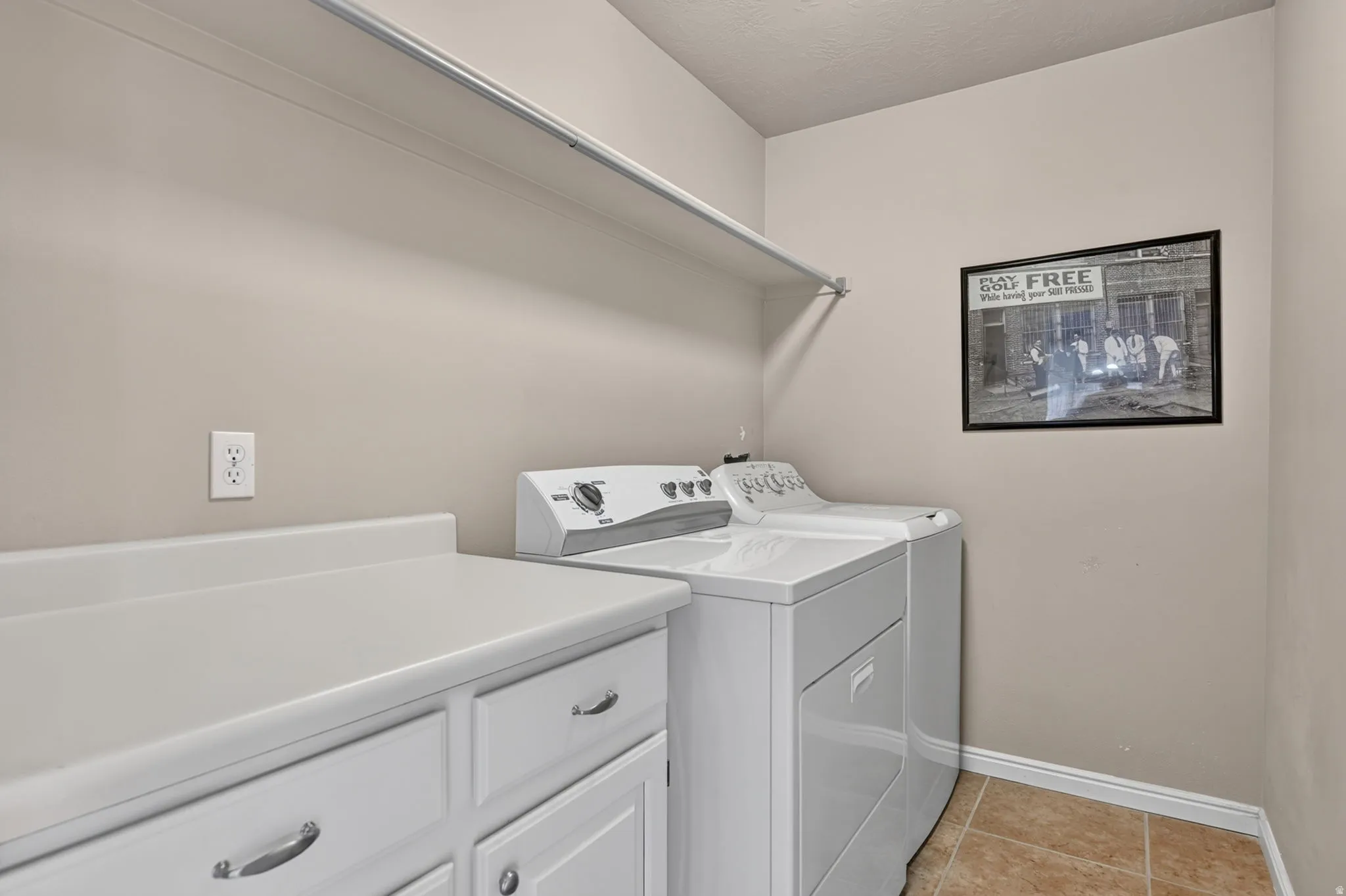 White cabinetry with pull hardware, light countertop, and tile flooring