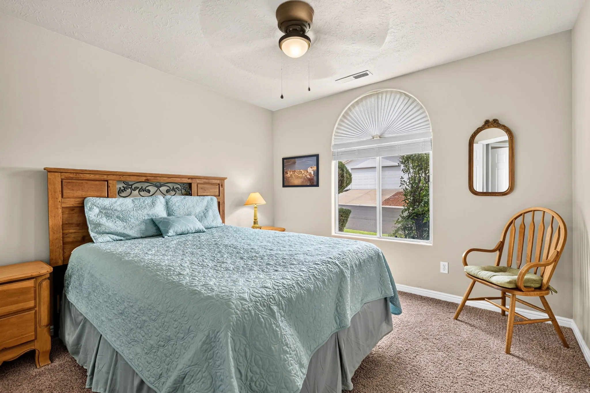 Arched window with privacy shade, ceiling fan with integrated lighting, and neutral wall tones