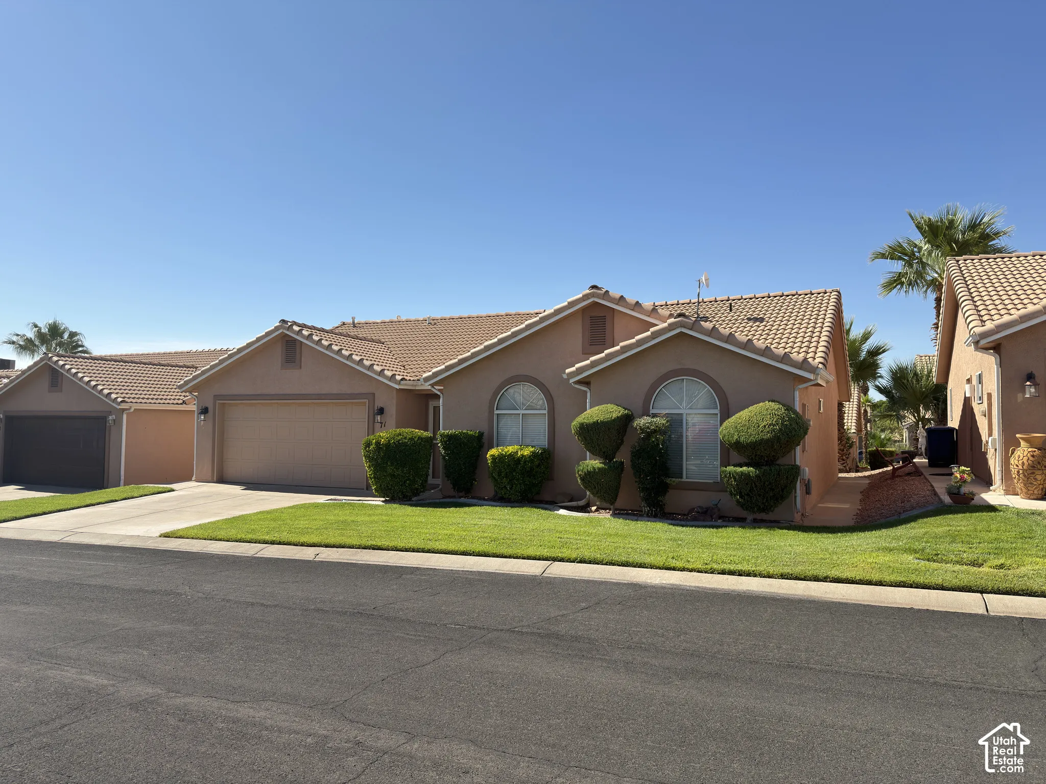 Stucco exterior with a tile roof, arched windows, and an attached garage