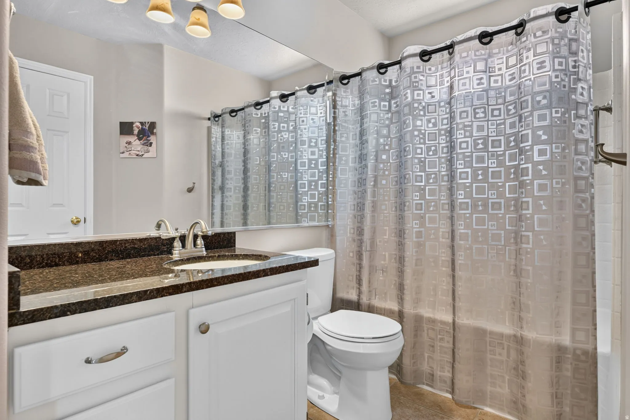 Vanity with dark countertop, undermount sink, and white cabinetry