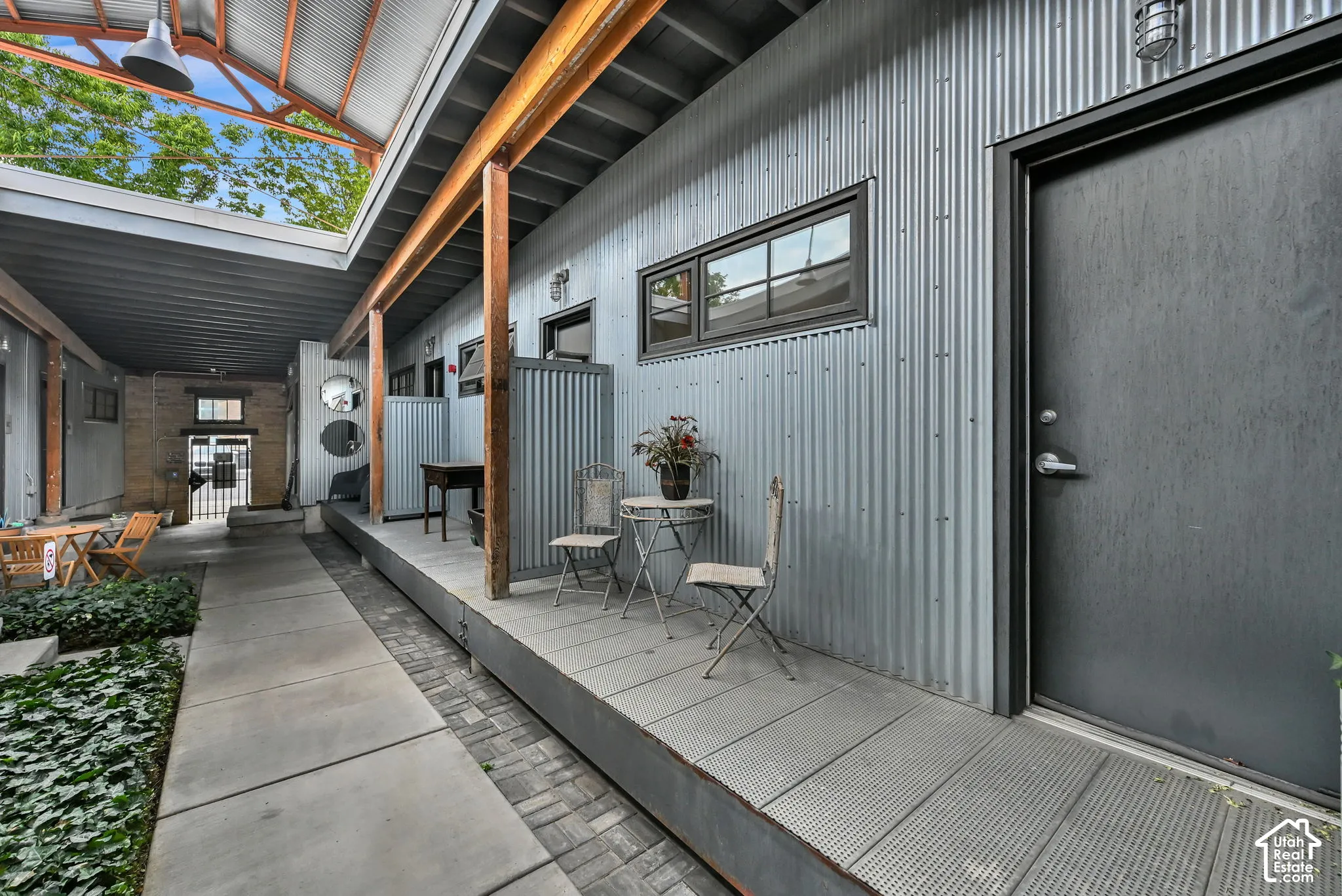Corrugated metal siding, exposed timber beams, and a concrete walkway create a distinctive exterior