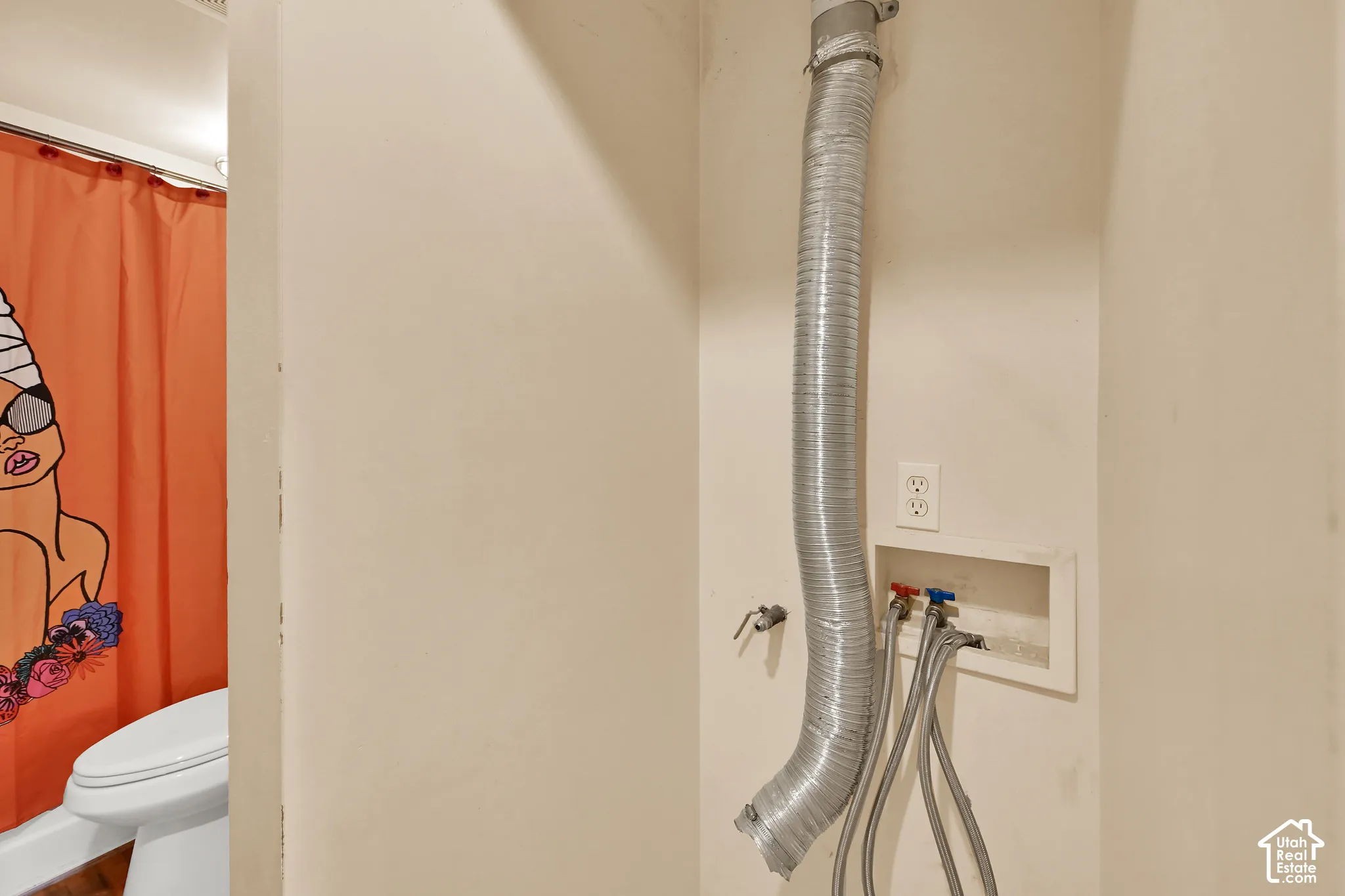 Utility area featuring exposed plumbing infrastructure with flexible supply lines, wall-mounted shut-off valves, and recessed electrical outlet for convenient access and maintenance