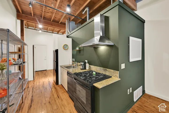 Exposed wood beam ceiling, hardwood flooring, stainless steel range hood, built-in dishwasher, and countertops
