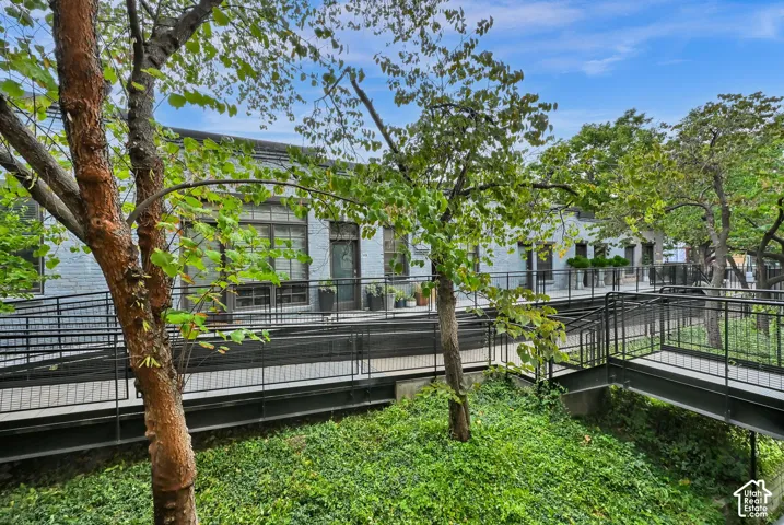 Lush outdoor living space featuring mature trees, manicured lawn, and multi-level composite decking with metal railings