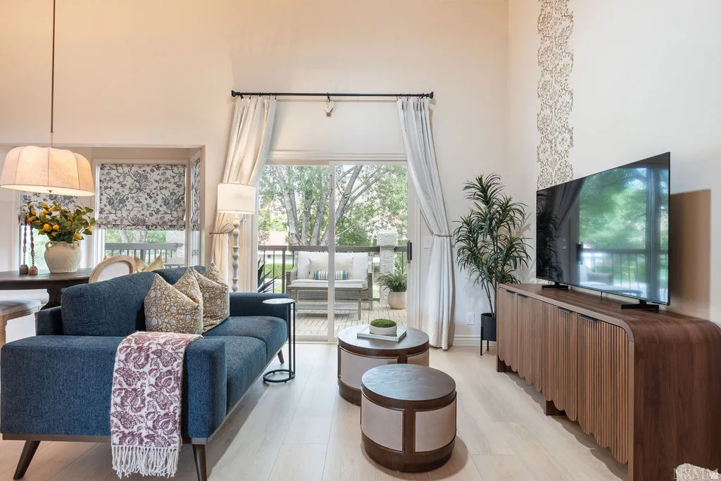 Vaulted ceiling, light-toned wood-finish flooring, sliding glass door to exterior, decorative wall paneling, and an elegant wood console