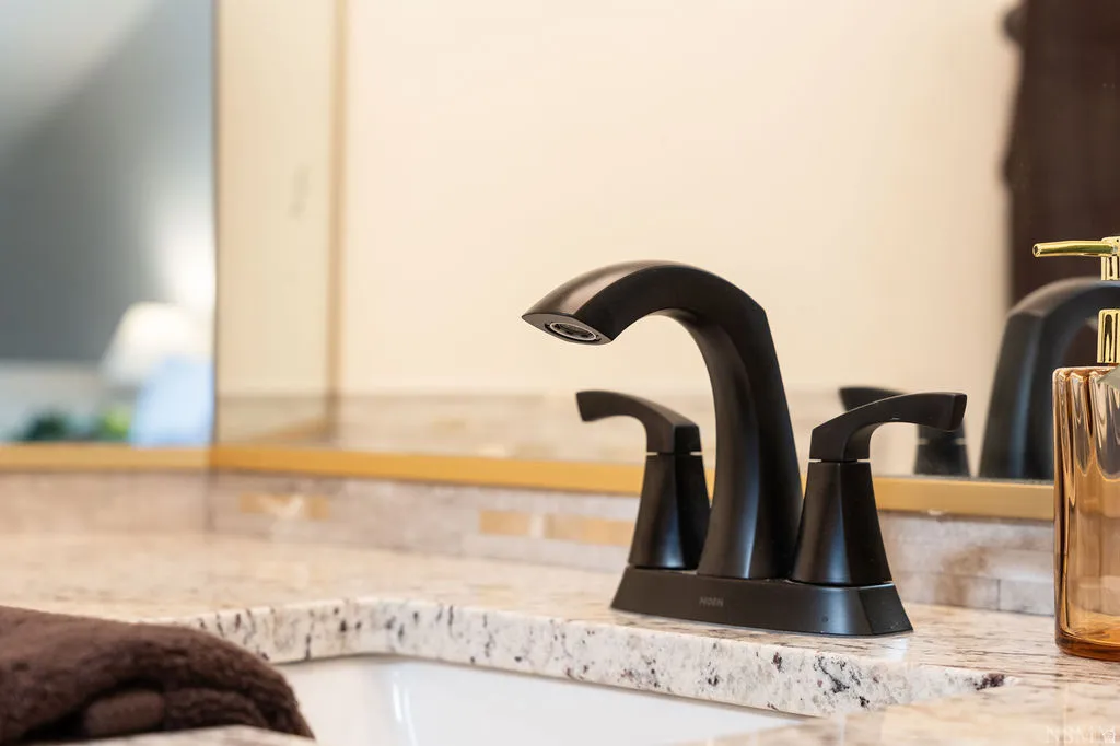 Under-mount sink with a speckled countertop, matte black faucet, and mosaic tile backsplash