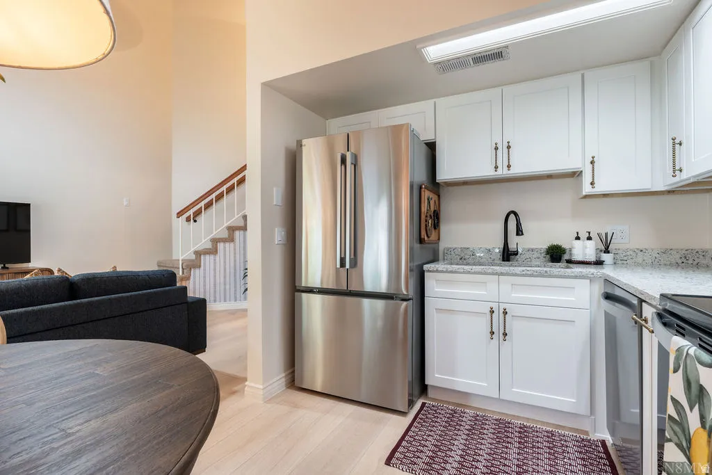 Updated kitchen featuring white shaker cabinetry, stainless steel appliances, granite countertops, and a black gooseneck faucet