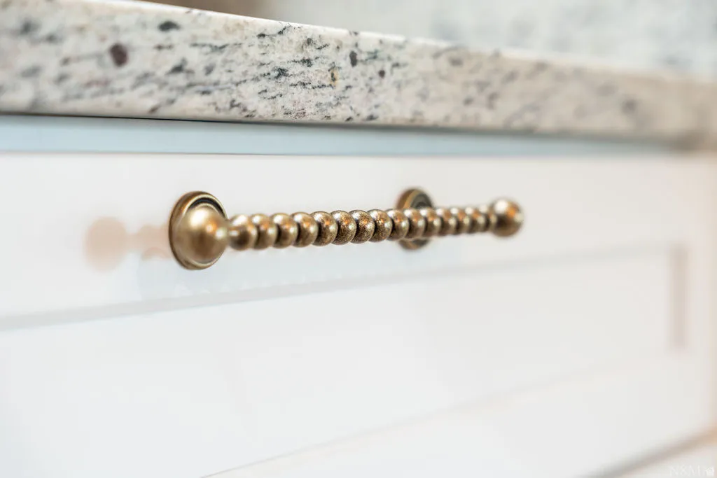 White cabinetry with bronze-finish hardware and a speckled countertop