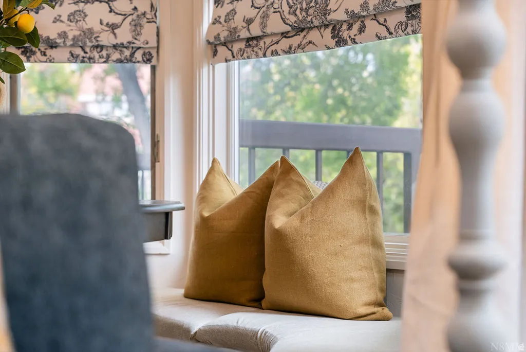 Window seat with upholstered cushion, decorative window treatments, and exterior railing