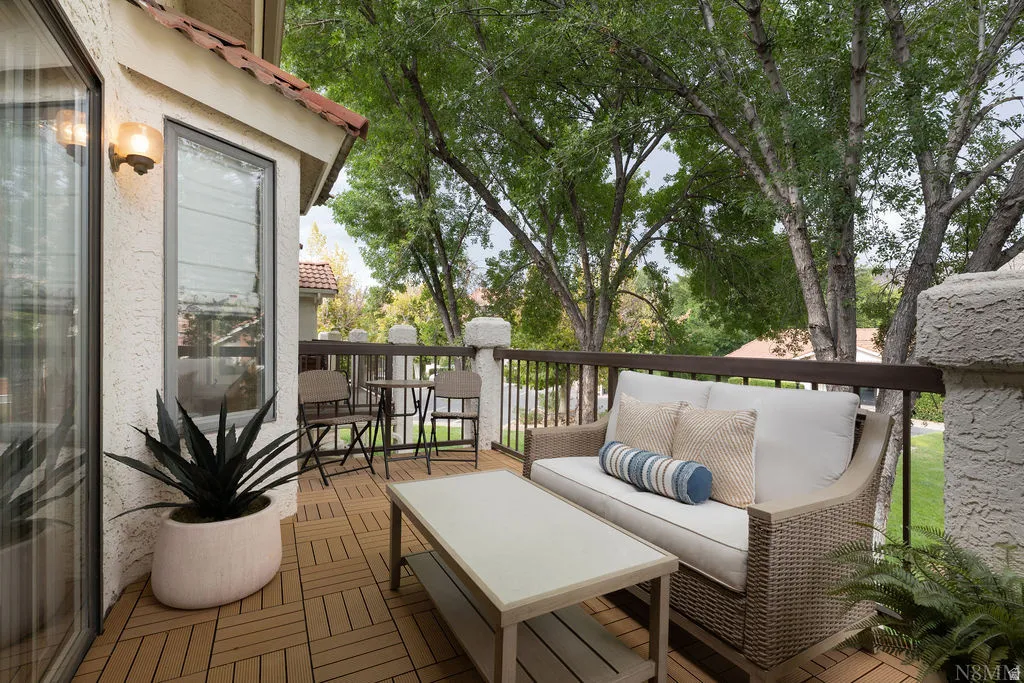 Exterior balcony featuring new decking, dark metal railing, and a textured stucco wall